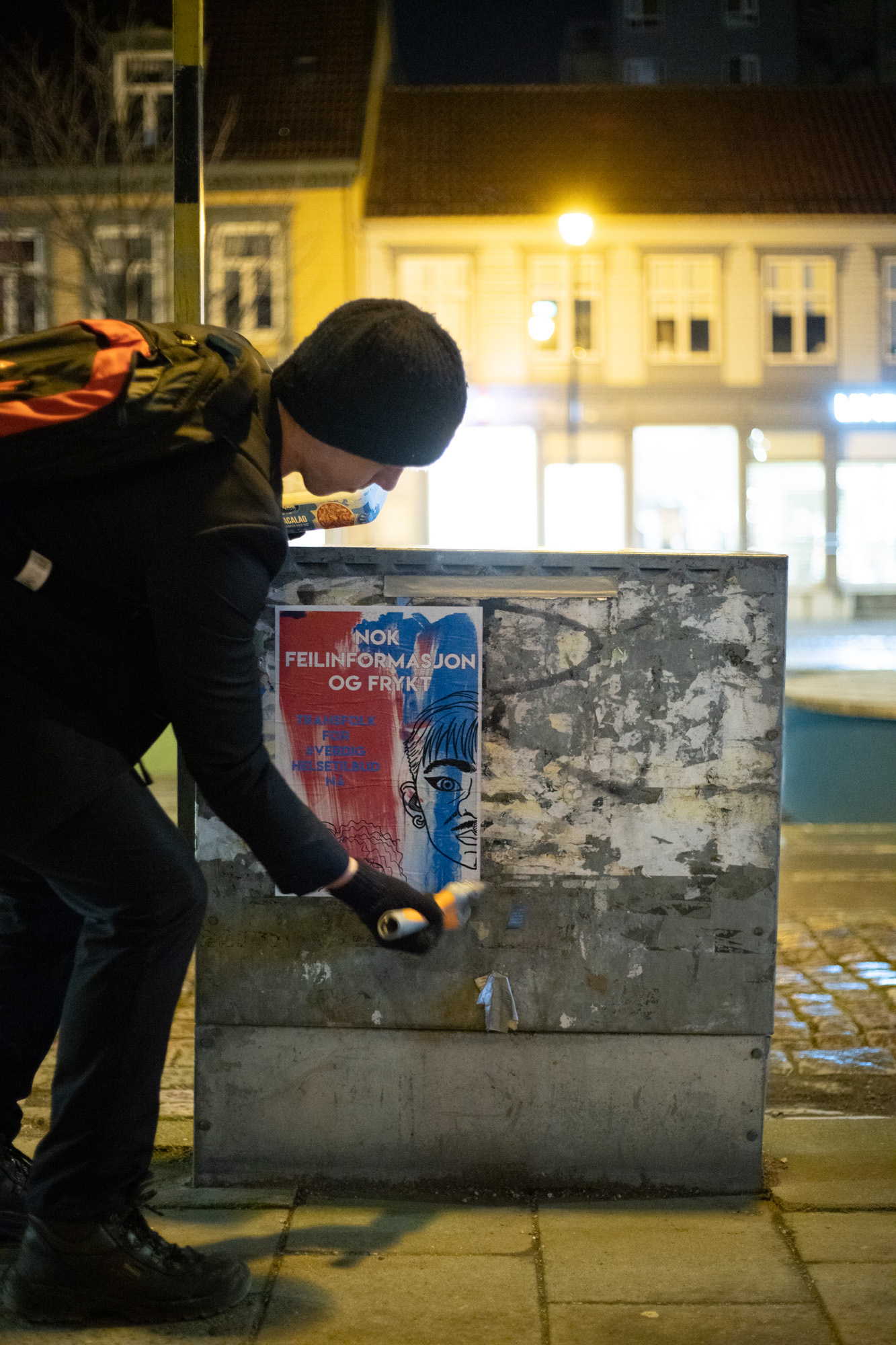 Bilde av en person som klistrer en plakat på en strømboks.